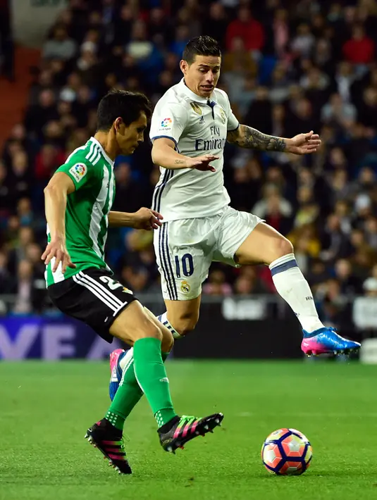 Gelandang Real Madrid, James Rodriguez berusaha merebut bola gelandang Real Betis, Serbia Aissa Mandi pada lanjutan La Liga Spanyol di Stadion Bernabeu, Madrid, (13/3). Real Madrid menang atas Real Betis dengan skor 2-1. (AFP Photo / Gerard Julien)