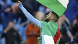 Gelandang Manchester City, Riyad Mahrez mengibarkan bendera Palestina saat merayakan timnya meraih gelar Liga Inggris di stadion Etihad, Minggu (23/5/2021). Pemain Aljazair ini melakukan hal tersebut bentuk dukungan kepada Palestina di tengah konflik dengan Israel. (AP Photo/Dave Thompson, Pool)