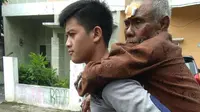 Petugas menggendong lansia tersebut saat mengantarkan ke rumahnya. (Istimewa)