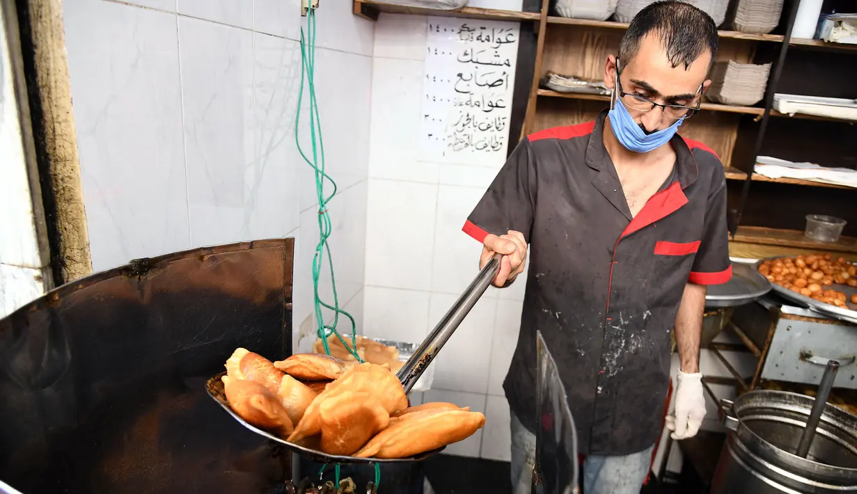 Seorang pedagang Suriah membuat "Qatayef", penganan manis tradisional yang biasa disajikan saat bulan suci Ramadan di Damaskus, Suriah, (18/5/2020). (Xinhua/Ammar Safarjalani)