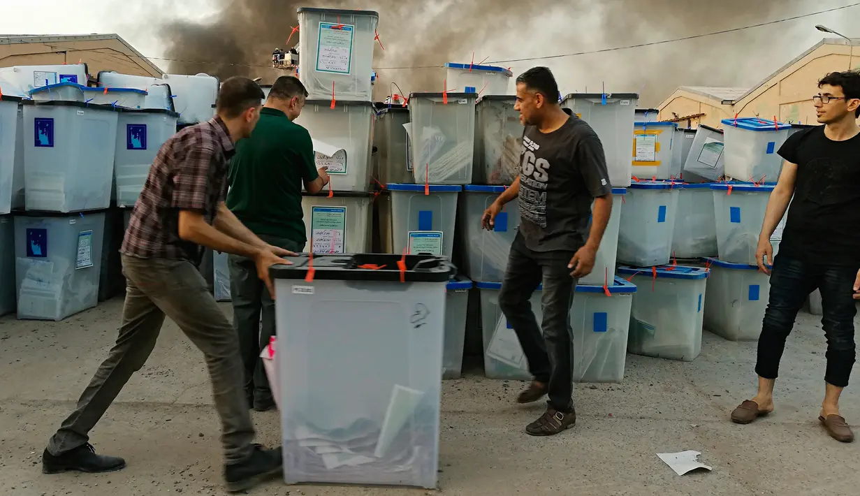Sejumlah petugas menyelamatkan kotak suara saat kebakaran gudang surat suara terbesar Irak di Baghdad, Minggu (10/6). Penyebab kebakaran di gudang penyimpanan itu juga masih belum jelas. (AP/Karim Kadim)
