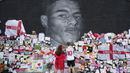 Sejumlah orang tampak menempelkan pesan dukungan dan meletakkan karangan bunga hingga pernak-pernik timnas Inggris di depan mural tersebut. (Foto:AP/Jon Super)