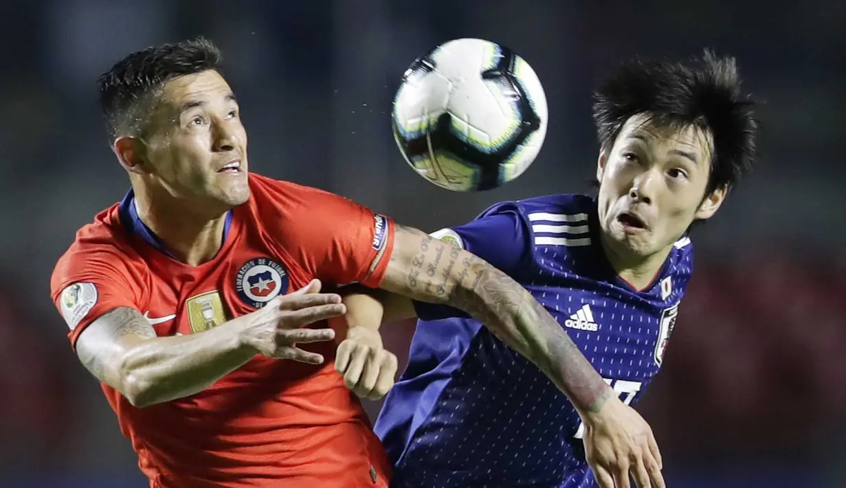 Gelandang Chili, Charles Aranguiz, duel udara dengan gelandang Jepang, Shoya Nakajima, pada laga Copa America 2019 di Stadion Morumbi, Selasa (18/7). Chili menang 4-0 atas Jepang. (AP/Andre Penner)