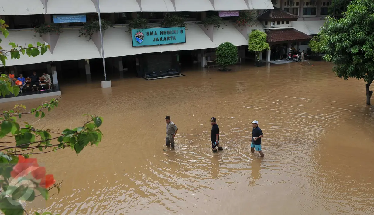 Sejumlah pengurus sekolah SMAN 8 Jakarta mengecek banjir kiriman yang menerjang sekolah mereka di Kelurahan Bukit Duri, Tebet, Jakarta, (8/3/2016). Akibat banjir tersebut, sekolah terpaksa diliburkan. (Liputan6.com/Gempur M Surya) 
