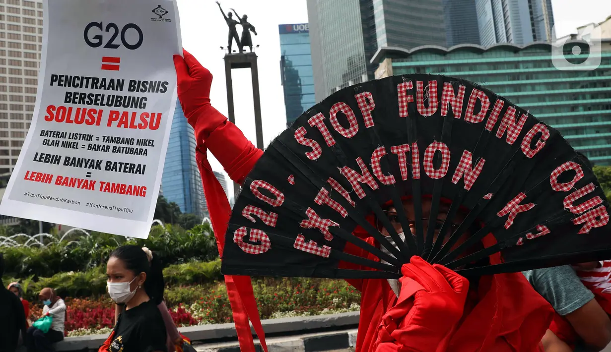 Aktivis iklim membawa poster saat melakukan aksi teatrikal di kawasan Bundaran Hotel Indonesia, Jakarta, Minggu (13/11/2022). Aksi yang digelar berbarengan dengan penyelenggaraan G20 ini meminta pemimpin dunia menemukan solusi bersama atas kondisi ekonomi global. (Liputan6.com/Herman Zakharia)