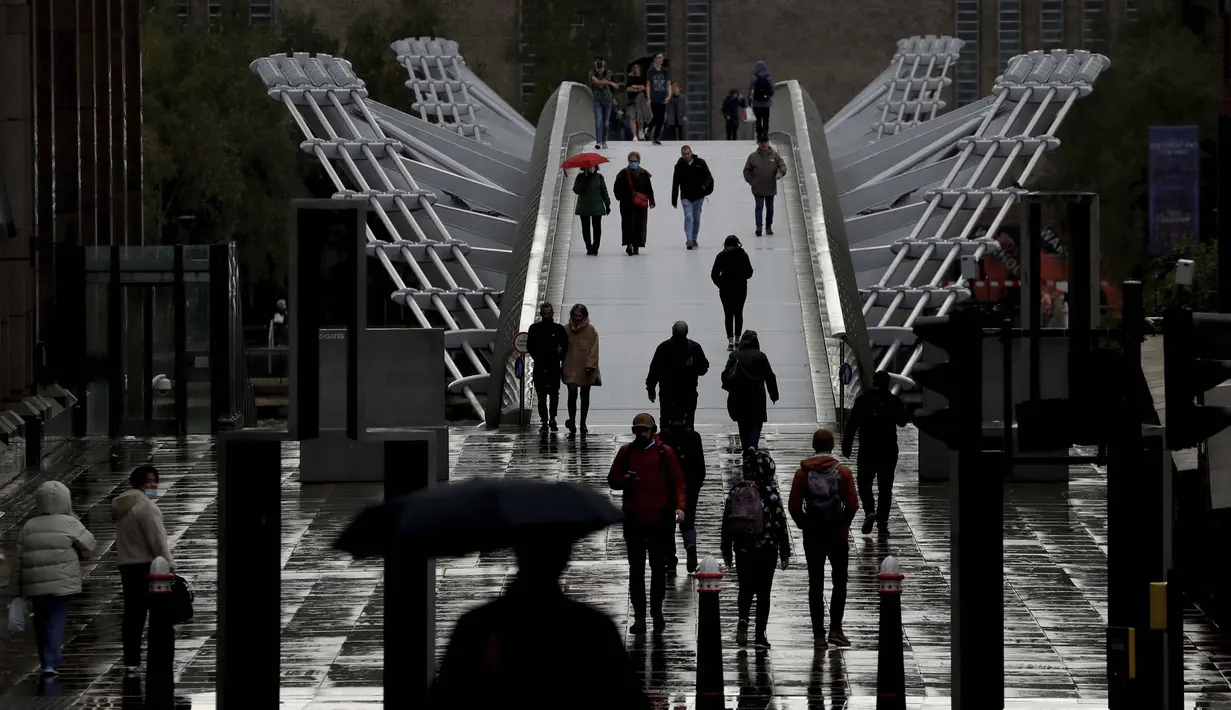 Orang-orang berjalan melintasi London Millennium Footbridge di London, Kamis (15/10/2020). London akan dipindahkan ke penguncian Tingkat 2 akibat virus corona COVID-19. (AP Photo/Matt Dunham)