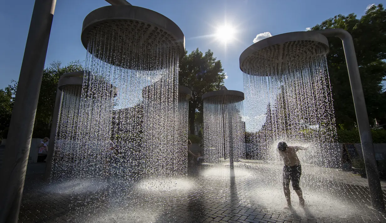 Seorang anak mendinginkan diri di air mancur umum di Vilnius, Lithuania, 26 Juni 2022. Gelombang panas berlanjut di Lithuania saat suhu naik hingga 32 derajat Celcius (89,6 derajat Fahrenheit). (AP Photo/Mindaugas Kulbis)