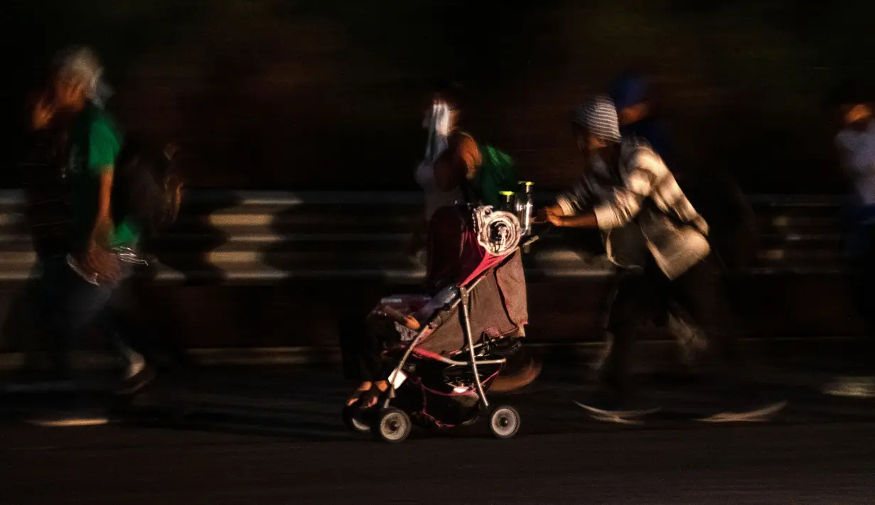 Imigran yang sebagian besar penduduk Honduras mendorong kereta bayi dalam perjalanan menuju AS di negara bagian Oaxaca, Meksiko, 29 Oktober 2018. Kereta dorong bayi telah menjadi barang mewah bagi para imigran dalam perjalanan mereka (Guillermo Arias/AFP)