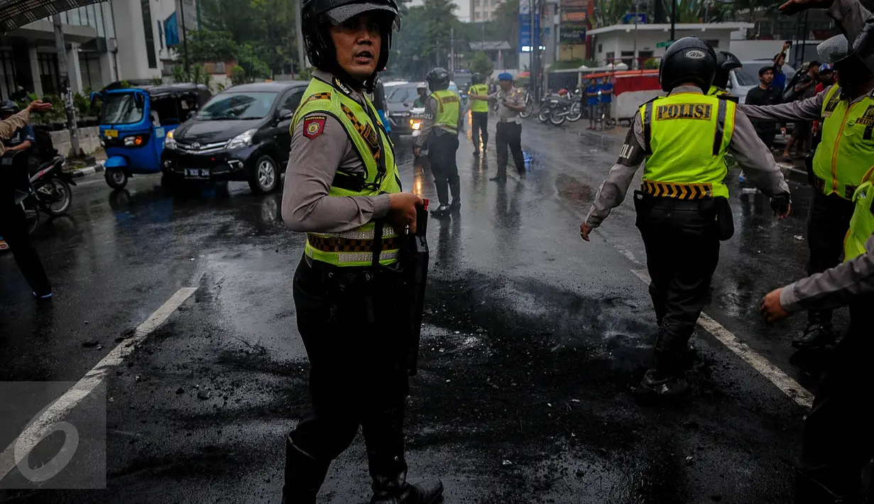 Polisi memadamkan aksi bakan ban yang dilakukan aktivis HMI di Jalan Cikini, Jakarta, Sabtu (8/10). Mereka menuntut Basuki Tjahaja Purnama (Ahok) mempertanggungjawabkan pernyataannya yang dinilai mencederai kitab suci Alquran. (Liputan6.com/Faizal Fanani)