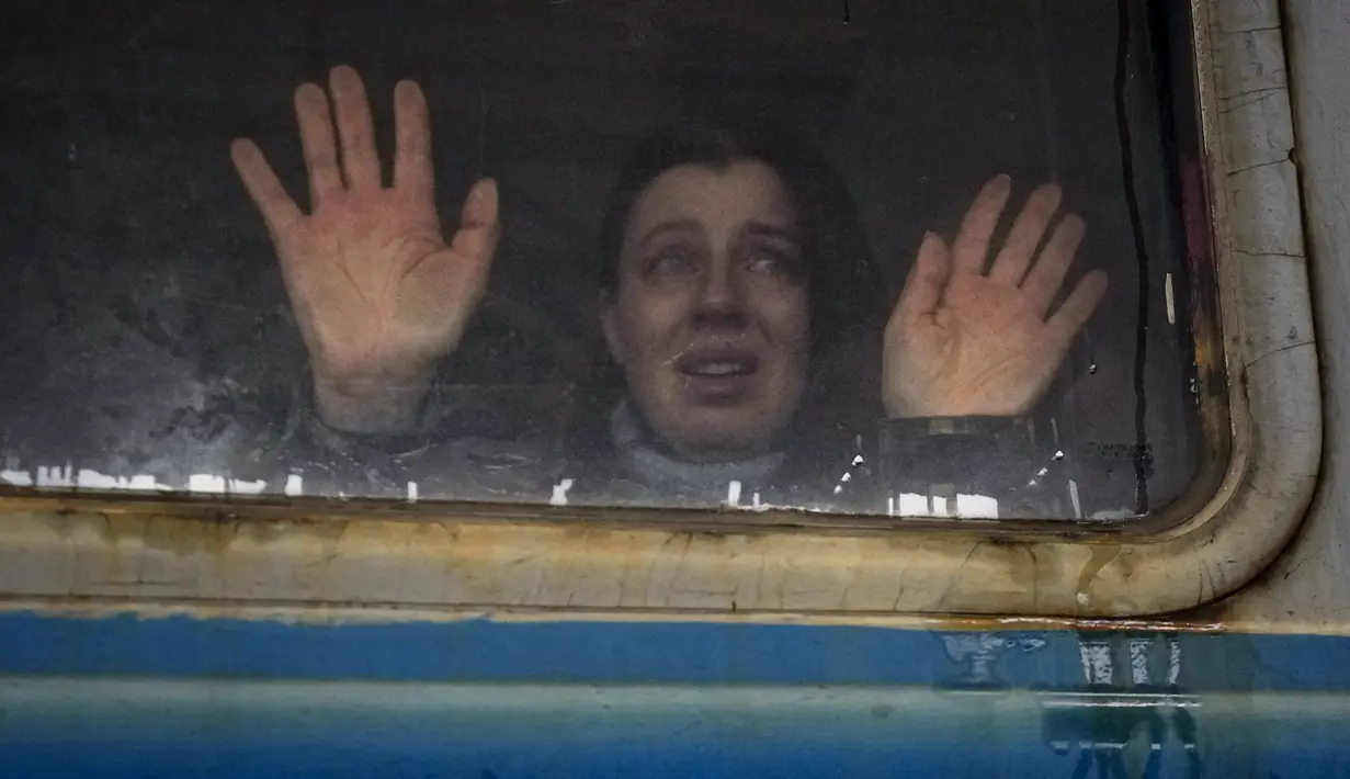 Seorang perempuan melihat ke arah kerabat dan menempelkan telapak tangannya ke jendela kereta menuju Lviv, di peron di Kiev, 3 Maret 2022. Sejumlah keluarga terpaksa terpisah, dengan mayoritas pria tetap tinggal di Ukraina untuk mempertahankan negaranya dari invasi Rusia.  (AP Photo/Vadim Ghirda)
