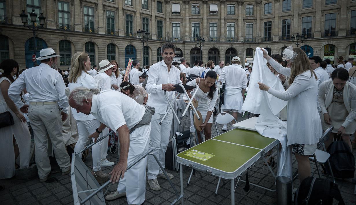 Peserta menyiapkan perlengkapan acara 'Diner en blanc' atau 'Makan Malam Putih' yang digelar di Place Vendome, Paris, Rabu (8/6). Ribuan orang mengenakan pakaian putih membawa meja, kursi dan keranjang penuh dengan makanan. (PHILIPPE LOPE/AFP)