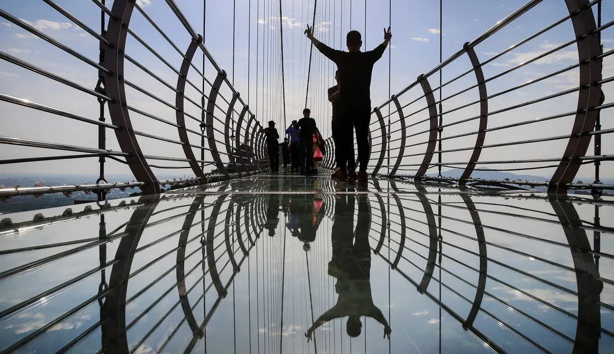 Foto pada 4 Mei 2019 memperlihatkan orang-orang mengambil gambar di atas jembatan berlantai kaca di Huaxi Adventure Park, Provinsi Jiangsu timur China. Jembatan kaca setinggi 518 meter ini menjadi tujuan wisata favorit di China. (Photo by STR / AFP)