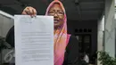 Warga perumahan Eks Yon Angkub, Cililitan Besar, Jakarta, menunjukan surat peringatan tertulis yang diberikan Kodam Jaya, Rabu (14/9). Warga di kawasan perumahan itu menolak eksekusi rumah yang akan dilakukan oleh Kodam Jaya. (Liputan6.com/Yoppy Renato)