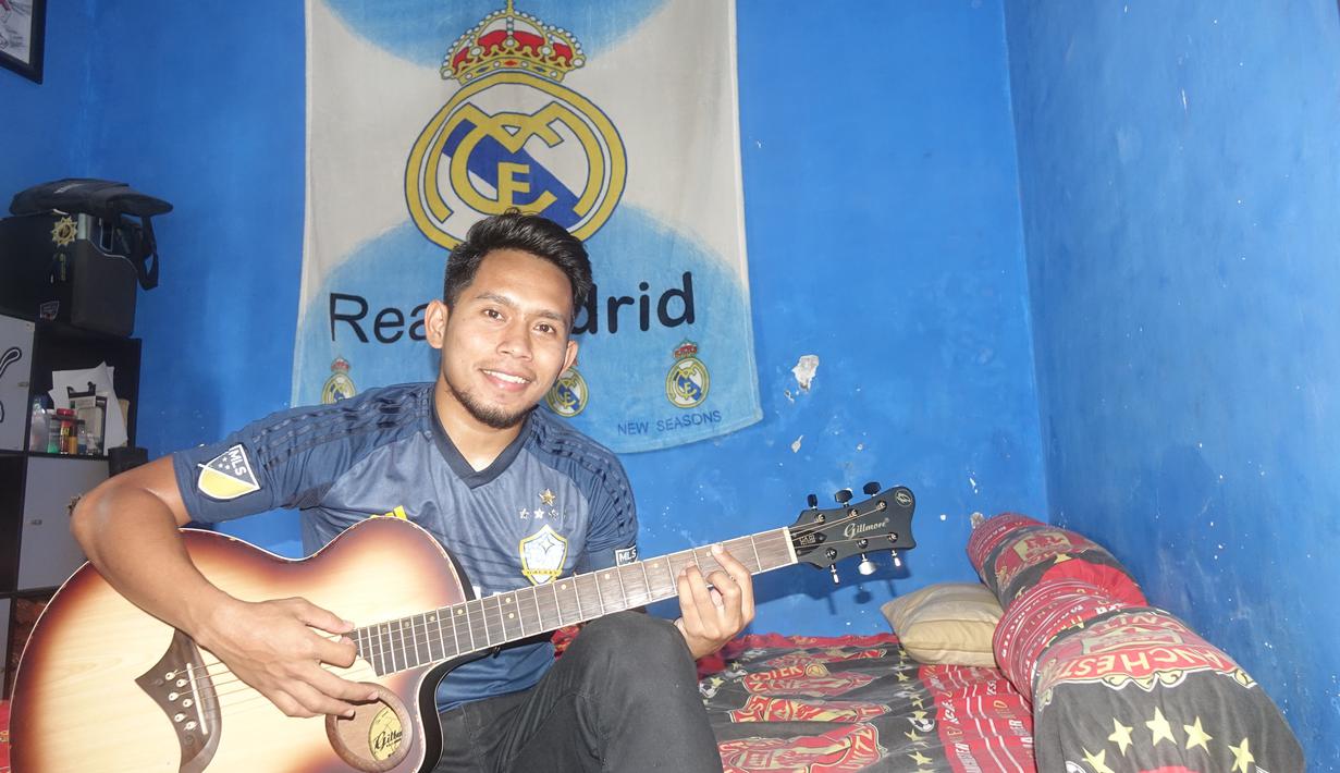 Andik Vermansah bersantai dalam kamarnya di rumah orang tuanya yang penuh dengan atribut Real Madrid dan Manchester United. (Bola.com/Zaidan Nazarul)