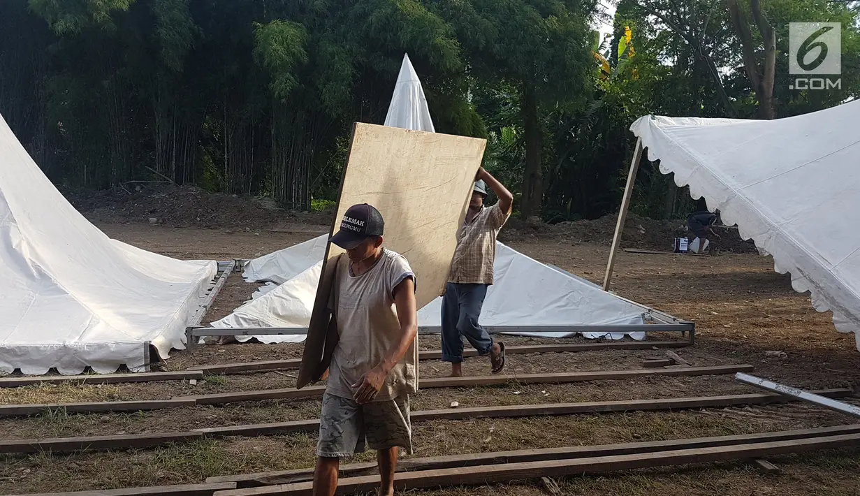 Pekerja mengangkat papan untuk menyelesaikan tenda relawan di Jalan Setiabudi, Medan, Senin (20/11). Menurut petugas bagian dekorasi, ada banyak tenda yang dipasang di 3 titik berbeda, seperti untuk tamu VIP, dan lokasi resepsi. (Liputan6.com/Aditya Eka)