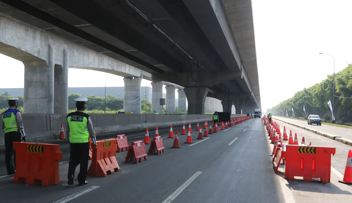Petugas kepolisian berjaga di pos penyekatan pemudik Tol Cikarang Barat, Kabupaten Bekasi, Jawa Barat, Minggu (9/5/2021).  Pemeriksaan dokumen kendaraan yang melintasi pos penyekatan pemudik guna memutus rantai penyebaran wabah COVID-19. (Liputan6.com/Herman Zakharia)