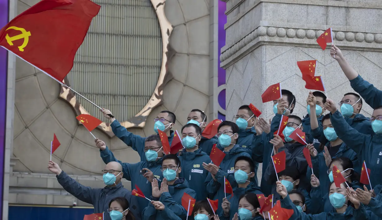 Para petugas medis yang datang dari luar Wuhan dalam membantu kota selama wabah virus corona COVID-19 megibarkan bendera China saat upacara perpisahan di Wuhan, Provinsi Hubei, China, Rabu (15/4/2020). Wuhan menjadi pusat penyebaran COVID-19. (AP Photo/Ng Han Guan)