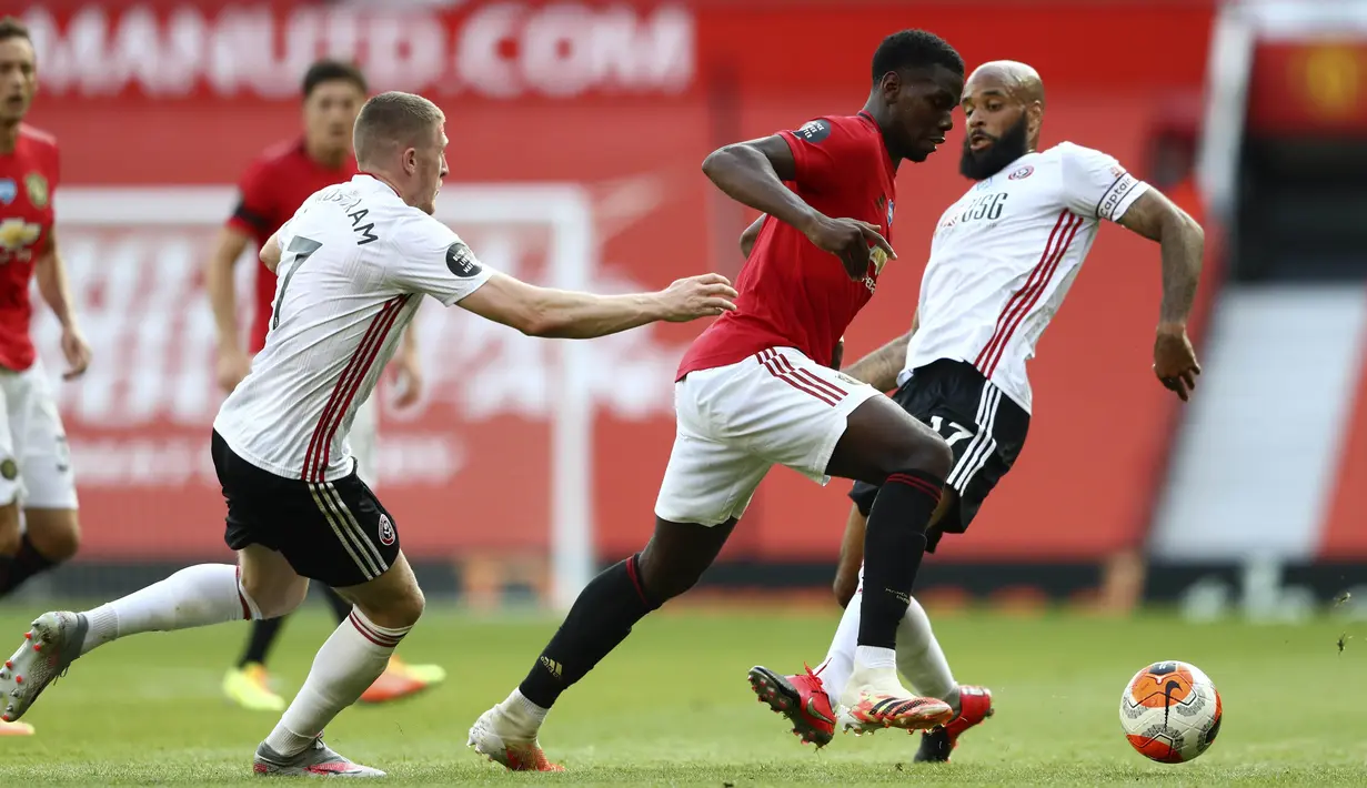 Gelandang Manchester United, Paul Pogba, berusaha melewati pemain Sheffield United pada laga Premier League di Stadion Old Trafford, Rabu (24/6/2020). Manchester United menang dengan skor 3-0. (AP/Michael Steele)