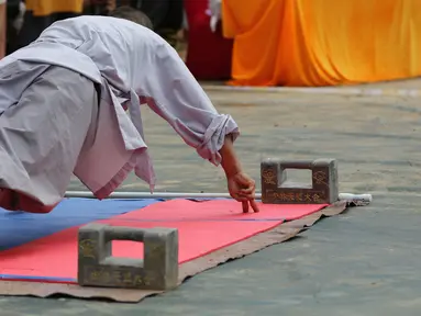 Seorang biksu menunjukkan kemampuann push up dengan dua jari selama kompetisi seni bela diri '72 Arts of Shaolin' di kuil Shaolin di Provinsi Henan, China, 30 Juli 2017. Kompetisi ini menampilkan para jago kungfu yang memamerkan kekuatan fisik. (STR AFP)