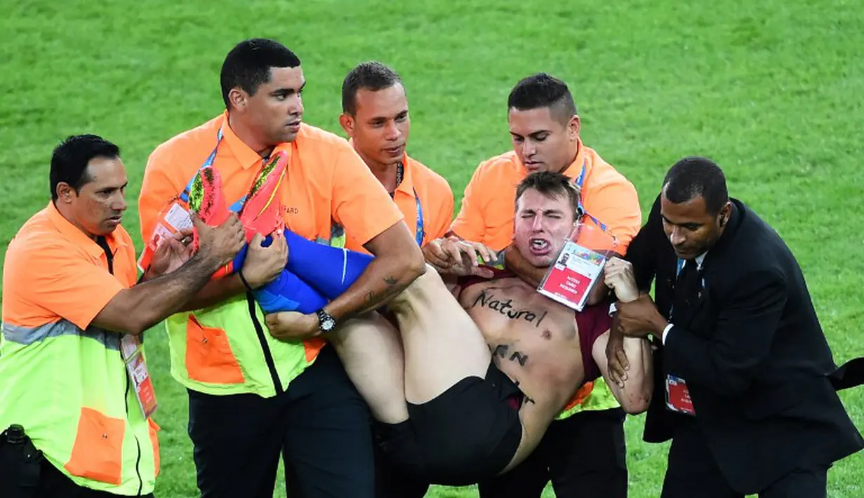 Butuh sekitar lima orang petugas untuk mengeluarkan fans nakal tersebut dari lapangan, Brasil, Senin (14/07/2014) (AFP PHOTO/CHRISTOPHE SIMON)
