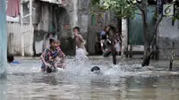 Anak- anak bermain saat banjir menggenangi kawasan Rawa Terate, Cakung Jakarta, Rabu (30/1). Banjir yang mencapai ketinggian pinggang orang dewasa terjadi sejak dini hari. (merdeka.com/Iqbal S. Nugroho)