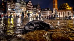 Masker dibuang di alun-alun Roemerberg di Frankfurt, Jerman, Rabu (29/12/2021). Kembang api tidak akan diizinkan di kota pada Malam Tahun Baru untuk menghindari penyebaran virus corona. (AP Photo/Michael Probst)