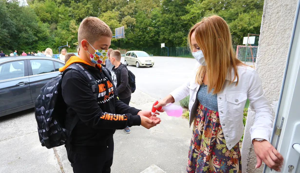 Seorang guru mendisinfeksi tangan siswa pada hari pertama tahun ajaran baru di Ozalj, Kroasia, 7 September 2020. Pembelajaran sekolah di Kroasia ditangguhkan sejak pertengahan Maret akibat wabah COVID-19. (Xinhua/Pixsell/Kristina Stedul Fabac)