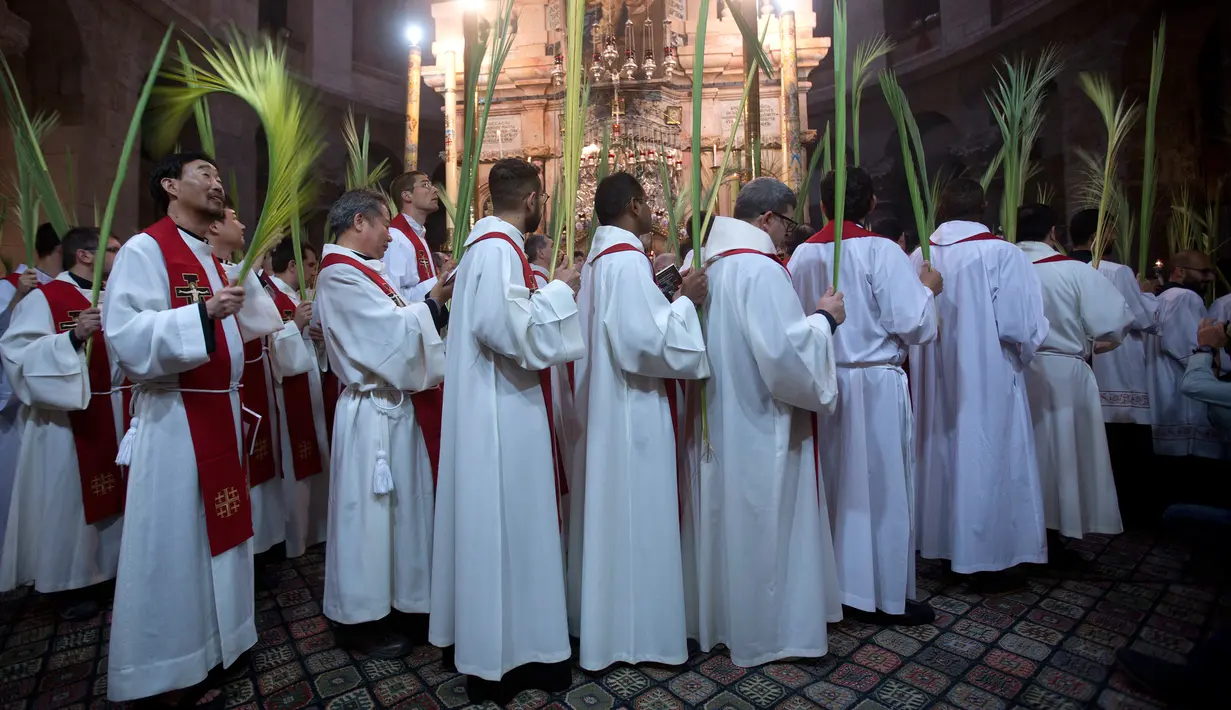 Pendeta Katolik Roma membawa daun palem selama prosesi Minggu Palma di Gereja Makam Kudus, Kota Tua Yerusalem, Minggu (25/3). Minggu Palma dirayakan setiap menjelang Paskah. (AP Photo/Oded Balilty)