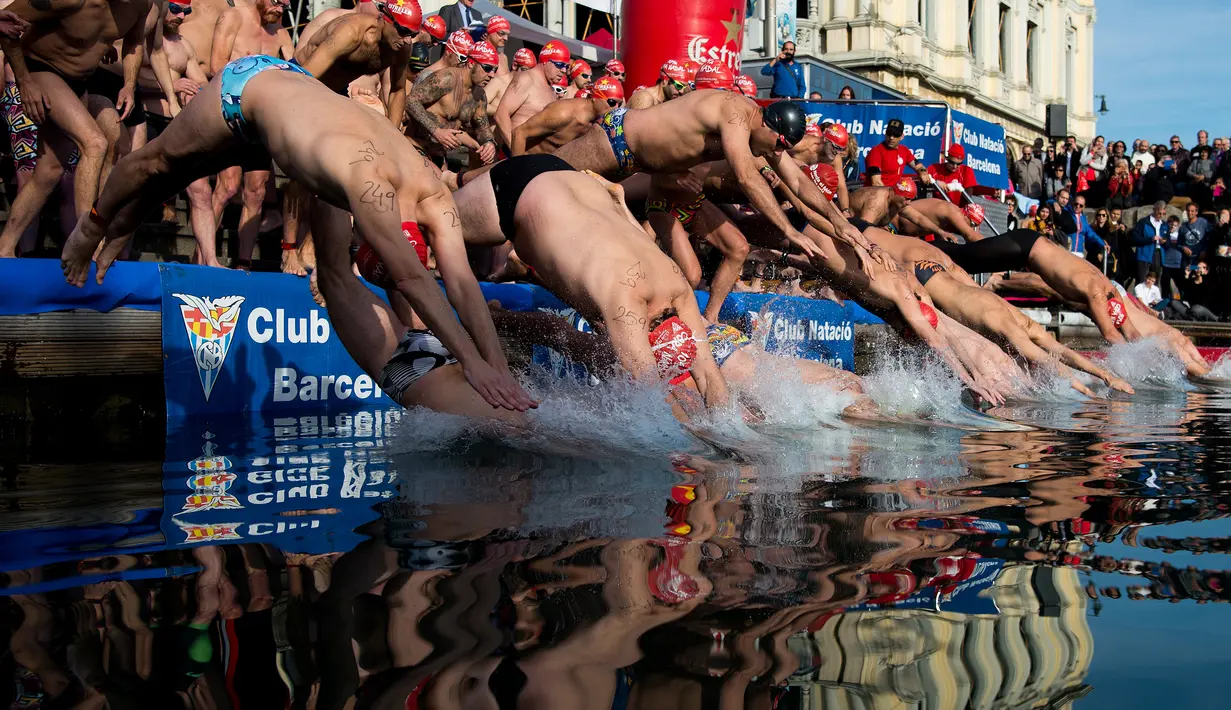 Para peserta melompat ke dalam air saat  kompetisi renang Copa Nadal di Port Vell Barcelona, Selasa (25/12). Lomba tradisional ini sudah menjadi tradisi lama yang mereka lakukan tiap tahun pada hari natal. (Josep LAGO / AFP)