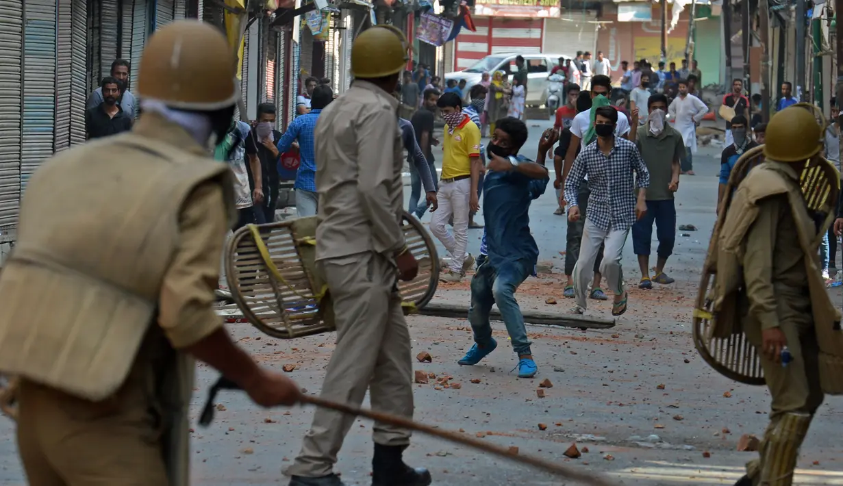 Seorang warga melemparkan batu ke arah polisi saat bentrok di Srinagar, India (11/7). Bentrokan bermula karena adanya kasus pembunuhan terhadap seorang pemberontak muda yang populer di India. (AFP PHOTO/Tauseef MUSTAFA)