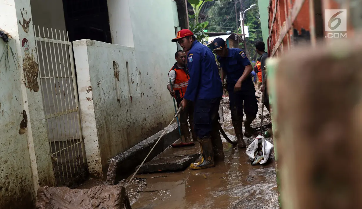 Petugas Damkar PB membersihkan lumpur sisa banjir di salah satu gang di kawasan Rawajati, Jakarta, Sabtu (27/4). Banjir akibat luapan air sungai Ciliwung sempat melanda kawasan ini pada Jumat (26/4). (Liputan6.com/Helmi Fithriansyah)