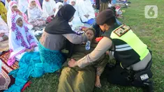Anggota polisi dari Polda Bali membantu warga yang pingsan saat melakukan shalat Idul Fitri di Lapangan Pegok, Sesetan, Denpasar, Sabtu (22/4/2023). (merdeka.com/Arie Basuki)