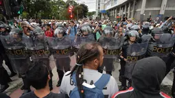 Massa berhadapan dengan polisi anti huru hara saat memprotes kenaikan tarif bus di Sao Paulo, Brasil, Selasa (12/1). Mereka protes karena di tengah krisis ekonomi, tarif transportasi angkutan bus justru naik. (AFP PHOTO/NELSON Almeida)