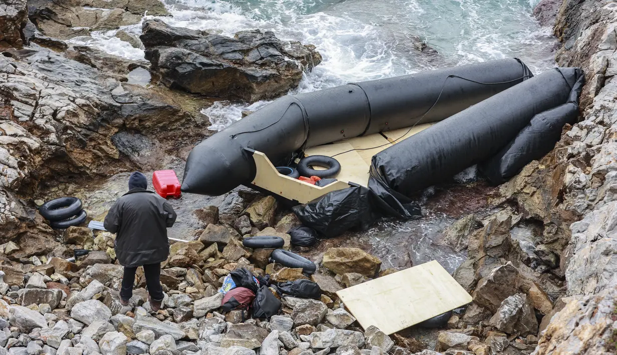 Seorang pria berdiri di samping perahu karet di Thermi di pulau Lesbos Yunani pada 7 Februari 2023. Tiga migran tewas dan lebih dari 20 orang dikhawatirkan hilang setelah perahu kedua tenggelam di lepas pantai Yunani hanya dalam beberapa hari, kata penjaga pantai. (Manolis Lagoutaris / AFP)