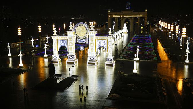 Orang-orang berjalan di VDNKh (Pameran Prestasi Ekonomi Nasional) yang didekorasi untuk perayaan Natal dan Tahun Baru di Moskow, Rusia, Jumat (27/11/2020). Area tersebut terbuat dari lapisan es buatan lebih dari 20.000 meter persegi. (AP Photo/Alexander Zemlianichenko)
