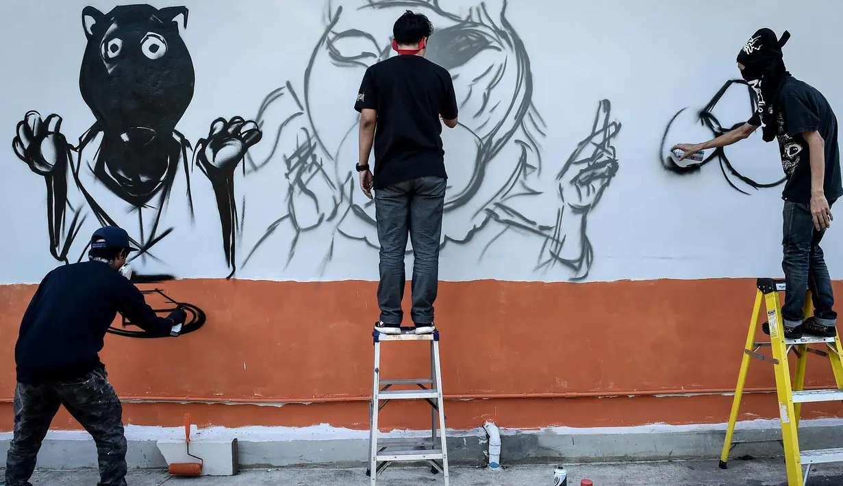 Sejumlah seniman grafiti membuat mural harimau kumbang di Bangkok, Thailand (16/3). Aksi ini sebagai protes perburuan liar ilegal oleh konglomerat konstruksi Premchai Karnasuta. (AFP Photo/Lillian Suwanrumpha)