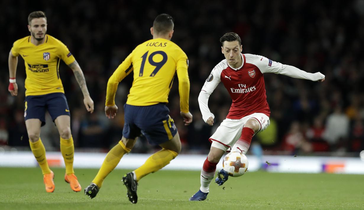 Pemain Arsenal, Mesut Ozil, berusaha melewati pemain Atletico Madrid, Lucas Hernandez, pada laga Liga Europa di Stadion Emirates, Kamis, (26/4/2018). (AP Photo/Matt Dunham)