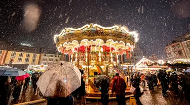 Salju turun saat Pasar Natal tradisional dengan komidi putar dibuka di Frankfurt, Jerman, Senin (27/11/2023). Pasar Natal adalah tradisi Eropa yang telah dilakukan selama berabad-abad. (AP Photo/Michael Probst)