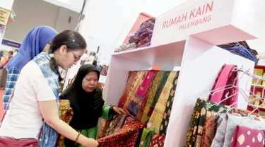 Pengunjung melihat produk Rumah Kain Palembang di booth YDBA pada Jakarta Fair Kemayoran 2019 di JIExpo Kemayoran, Jakarta, Rabu (19/6/2019). YDBA mengikutsertakan 40 UMKM mulai dari produk fashion, aksesoris, kerajinan, alat rumah tangga hingga makanan hingga 30 Juni 2019. (Liputan6.com/HO/Eko)