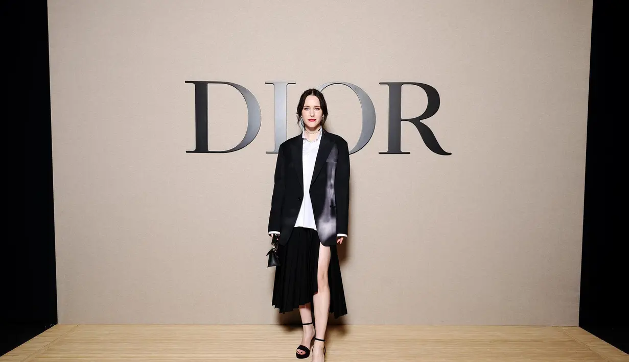 Rachel Brosnahan tampil lebih artsy dengan jaket hitam, rok hitam dan kemeja katun putih. [Dior]