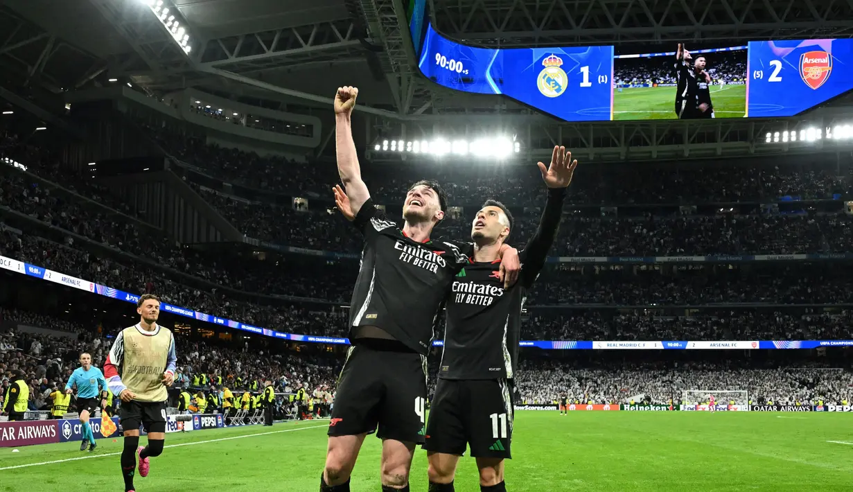 Pemain Arsenal, Gabriel Martinelli (kanan) bersama Declan Rice merayakan yang gol kedua bagi timnya saat pertandingan leg kedua perempat final Liga Champions 2024/2025 melawan Real Madrid di Stadion Santiago Bernabeu, Madrid, Spanyol pada 16 April 2025 atau Kamis 17 April 2025 dini hari WIB. (JAVIER SORIANO/AFP)