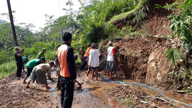 Ratusan warga menyingkirkan lumpur dan material lain yang menimpa jalan penghubung dua desa. (Foto: Liputan6.com/BPBD Banyumas/Muhamad Ridlo)