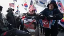 Pengunjuk rasa anti-Korea Utara merobek bendera Korea Utara saat melakukan aksi menyambut kedatangan kapal feri Korea Utara yang membawa rombongan seni untuk tampil di Olimpiade Musim Dingin Pyeongchang 2018, Korea Selatan (6/2). (AFP/Ed Jones)