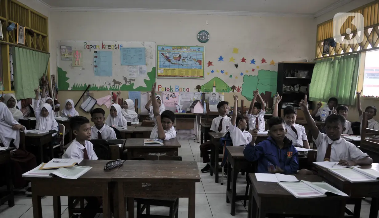 Siswa korban banjir mengangkat tangan saat ditanya oleh guru di SDN Bukit Duri 11, Jakarta, Senin (6/1/2020). Banjir menyebabkan sekitar 50 persen siswa SDN Bukit Duri 11 tidak masuk sekolah karena mayoritas tinggal di kawasan Kampung Melayu dan Kampung Pulo. (merdeka.com/Iqbal S. Nugroho)