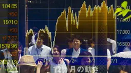 Beberapa orang tercermin dalam papan yang menampilkan indeks pasar saham terbesar di Tokyo, Jepang, Jumat, (10/7/2015). Meskipun Nikkei mengalami kenaikan pada Jumat pagi, tetapi tertutupi oleh penurunan tajam di Fast Retailing Co. (REUTERS/Thomas Peter)