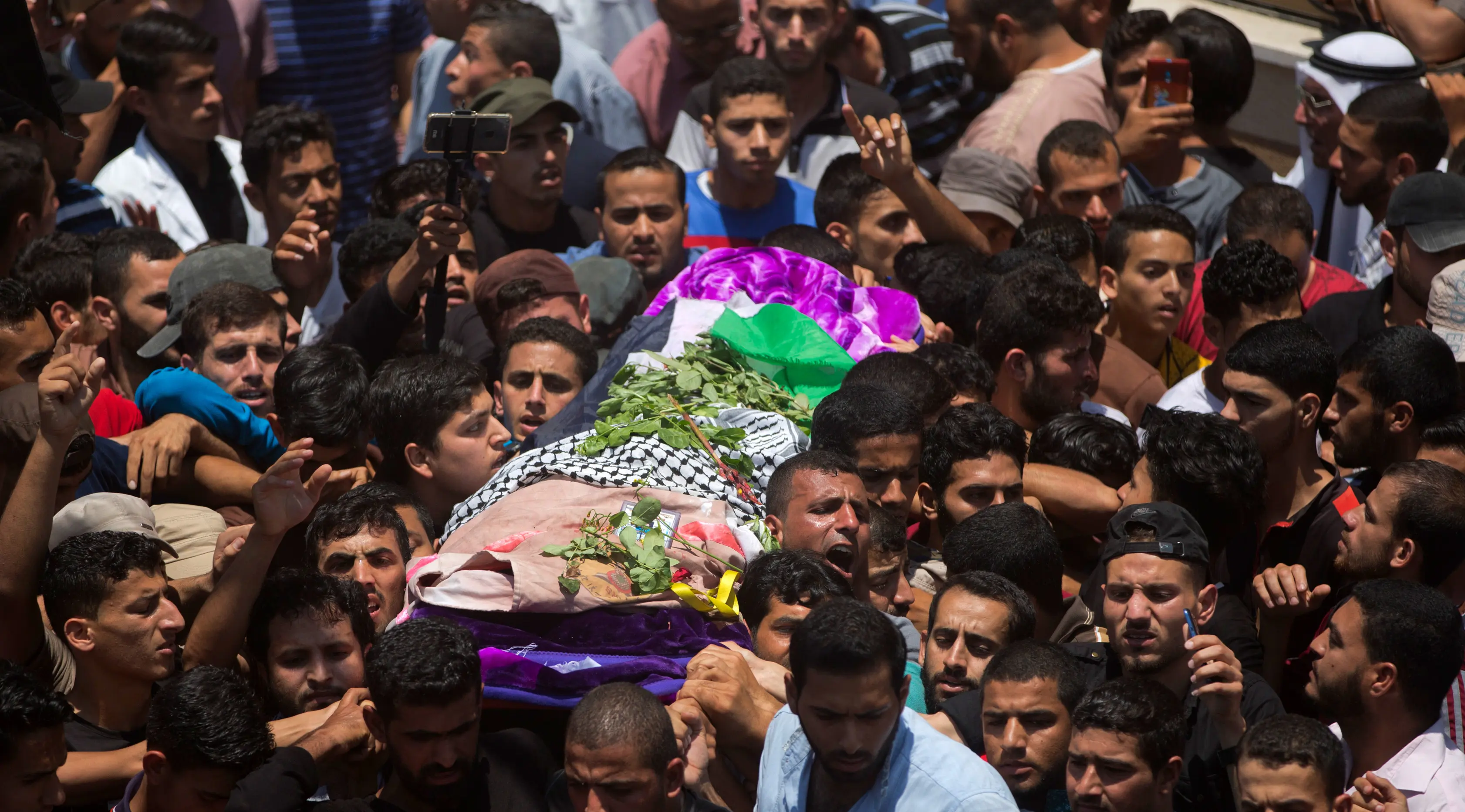 Ribuan pelayat membawa jasad perawat Palestina, Razan Najjar saat pemakamannya di Kota Khan Younis, Jalur Gaza Selatan, Sabtu (2/6). Gadis 21 tahun tersebut terbunuh oleh tembakan Israel pada Jumat, 1 Juni 2018. (AP Photo/Khalil Hamra)