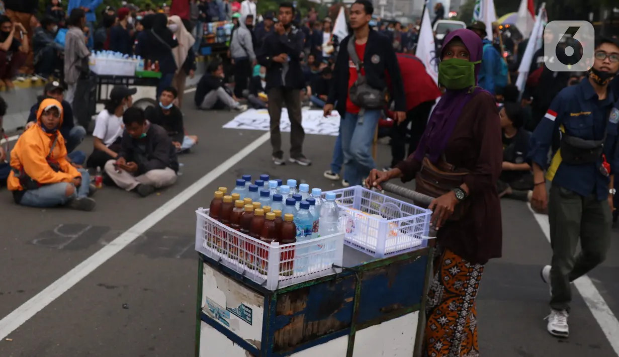 Pedangang menawarkan dagangannya kepada massa aksi saat demo penolakan omnibus law di kawasan patung kuda, Jakarta, Selasa (20/10/2020). Para pedagang kaki lima memanfaatkan moment aksi massa untuk mencari ke untungan meskupun sangat membahayakan bagi keselamatan mereka. (Liputan6.com/Angga Yuniar)
