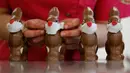 Pekerja menyelesaikan pembuatan cokelat paskah berbentuk kelinci yang mengenakan masker di toko roti Baeckerei Bohnenblust di Bern, Swiss, Jumat (27/3/2020). Di kemasannya dipasang sebuah kertas bertuliskan cara melindungi diri untuk mencegah penularan virus corona. (STEFAN WERMUTH/AFP)