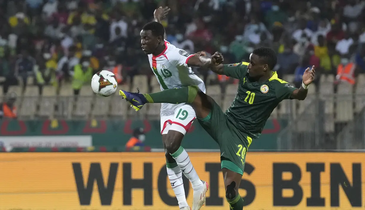 Bek Senegal, Bouna Sarr (kanan) berebut bola dengan pemain Burkina Faso, Hassane Bande pada pertandingan semifinal Piala Afrika 2022 di stadion Ahmadou Ahidjo di Yaounde, Kamerun, Kamis (3/2/2022). Senegal menang atas Burkina Faso 3-1 dan lolos ke final. (AP Photo/Themba Hadebe)