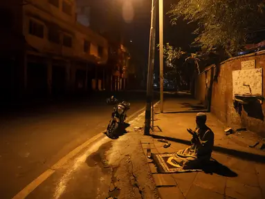 Seorang pria Muslim berdoa di jalan di luar Masjid Jama pada hari pertama Ramadan selama penguncian nasional untuk mengendalikan penyebaran virus corona Covid-19, di New Delhi, India (25/4/2020). (AP Photo/Manish Swarup)